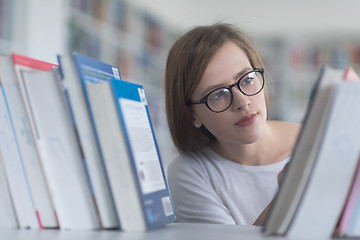 Image showing portrait of famale student selecting book to read in library