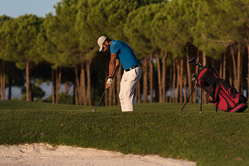 Image showing golfer hitting a sand bunker shot on sunset