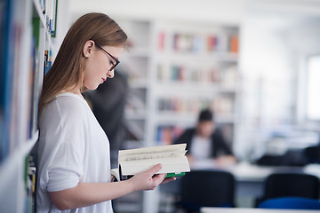 Image showing portrait of famale student reading book in library