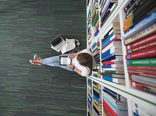 Image showing female student study in library, using tablet and searching for 