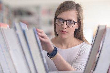 Image showing portrait of famale student selecting book to read in library