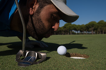 Image showing golf player blowing ball in hole