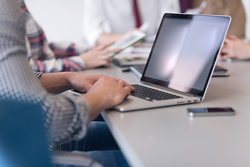 Image showing close up of business man hands typing on laptop with team on mee