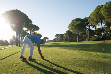 Image showing golf player placing ball on tee