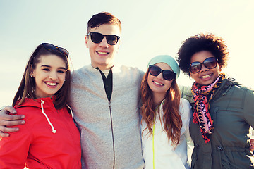 Image showing happy teenage friends in shades hugging outdoors