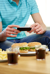 Image showing close up of man with smartphone picturing food