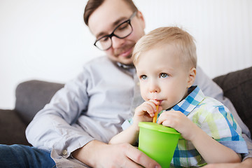 Image showing father and son drinking from cup at home