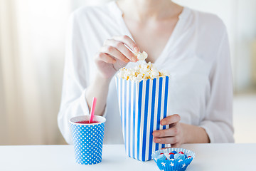 Image showing woman eating popcorn with drink and candies