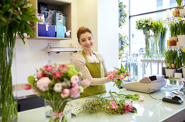 Image showing smiling florist woman making bunch at flower shop