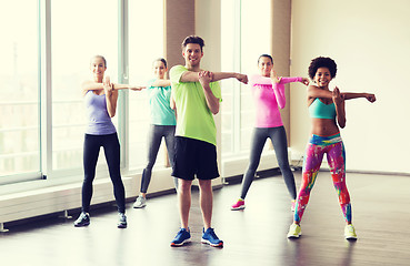 Image showing group of smiling people stretching in gym