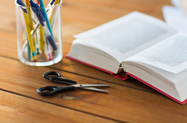 Image showing close up of pens, book and scissors on table