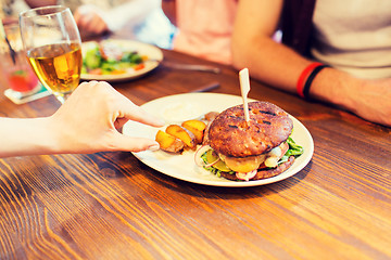 Image showing close up of friends hands sharing burger at bar