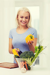 Image showing smiling young woman cooking vegetables at home