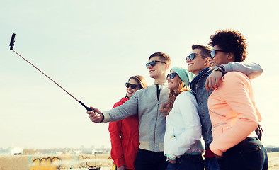 Image showing friends taking selfie with smartphone on stick