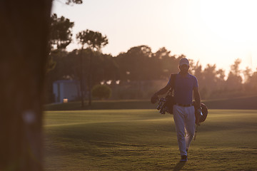 Image showing golfer  walking and carrying golf  bag at beautiful sunset