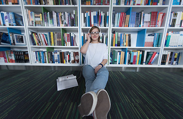 Image showing female student study in library, using tablet and searching for 