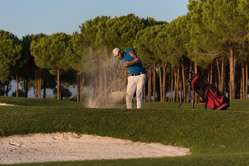 Image showing golfer hitting a sand bunker shot on sunset