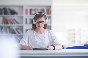 Image showing female student study in library, using tablet and searching for 