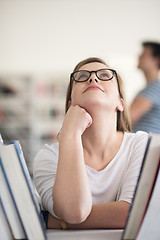 Image showing portrait of famale student selecting book to read in library