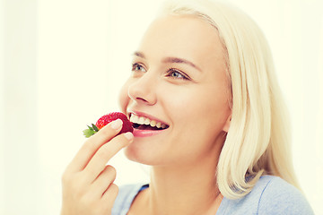 Image showing happy woman eating strawberry at home