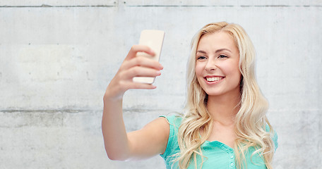 Image showing smiling young woman taking selfie with smartphone