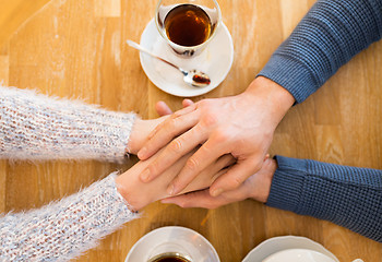 Image showing close up of couple holding hands at restaurant