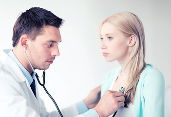 Image showing doctor with stethoscope listening to the patient