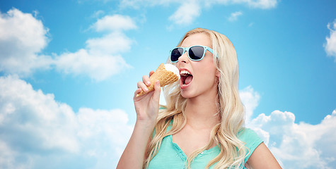 Image showing happy young woman in sunglasses eating ice cream