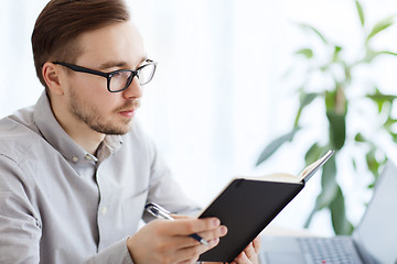 Image showing creative male worker with book at home office