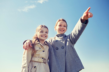 Image showing happy little girls hugging and pointing finger