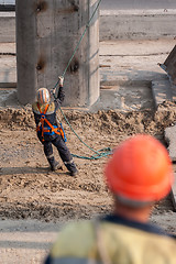 Image showing Worker pulls rope to level panel lifted by crane