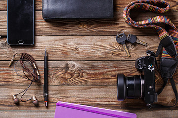 Image showing Travel concept - headphones, camera,  sketchbook, purse, pencil and keys on wooden background.