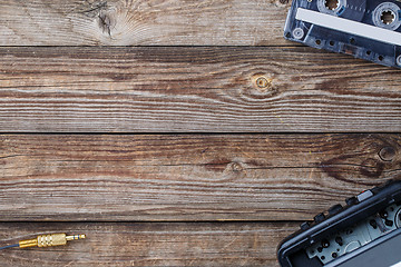 Image showing Cassette tape, cassette player and headphones over wooden table. top view.