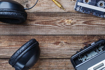 Image showing Cassette tapes, cassette player and headphones over wooden table. top view.