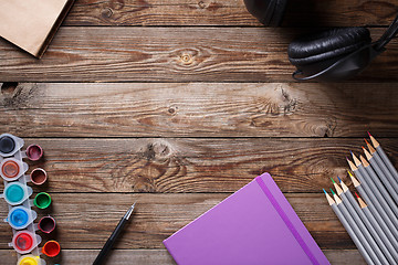 Image showing Watercolors, color pencils and sketchbook on wooden table. Flat lay photo with empty space for logo, text.