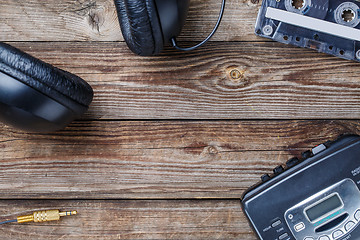 Image showing Cassette tapes, cassette player and headphones over wooden table. top view.