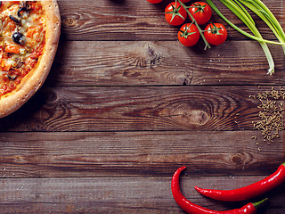 Image showing Italian pizza with tomatoes on a wooden table, top view.