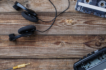 Image showing Cassette tape, cassette player and headphones over wooden table. top view.