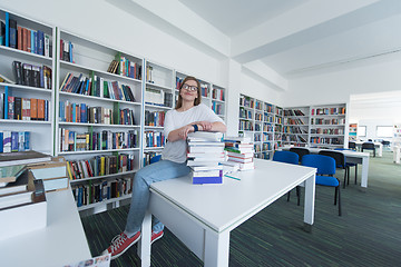 Image showing female student study in library, using tablet and searching for 