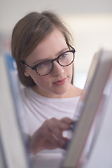 Image showing portrait of famale student selecting book to read in library