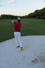 Image showing golfer hitting a sand bunker shot on sunset