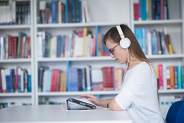 Image showing female student study in library, using tablet and searching for 