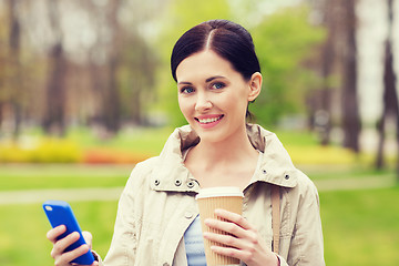 Image showing smiling woman with smartphone and coffee in park