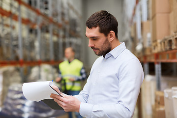 Image showing businessman writing to clipboard at warehouse