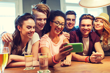 Image showing happy friends with smartphone taking selfie at bar