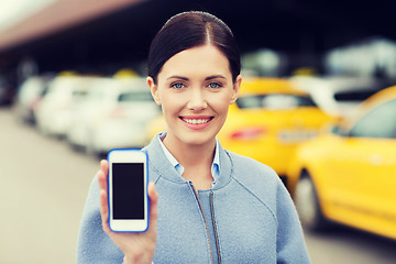 Image showing smiling woman showing smartphone over taxi in city