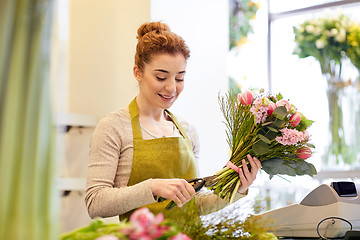 Image showing smiling florist woman making bunch at flower shop