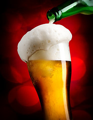 Image showing Pouring beer on red background