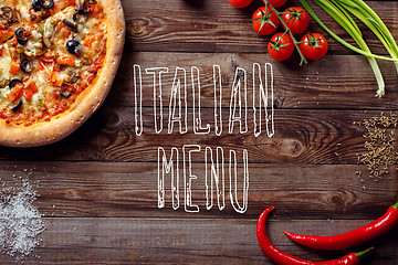 Image showing Italian pizza with tomatoes on a wooden table, top view, close-up