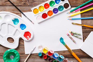 Image showing Paper, watercolors, paint brush and some art stuff on wooden   table